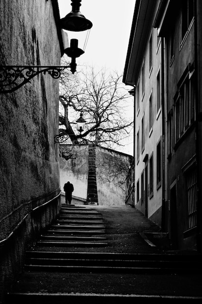 Vertikale Graustufenaufnahme einer Treppe zwischen zwei Gebäuden, die nach oben führt