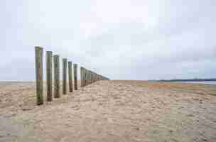 Kostenloses Foto vertikale holzbretter eines unfertigen decks am strand unter einem bewölkten himmel