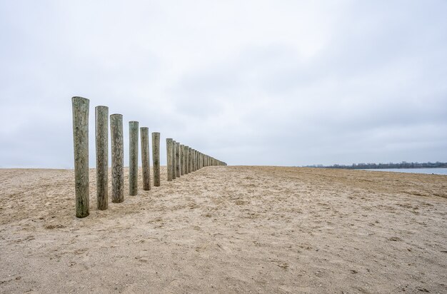 Vertikale Holzbretter eines unfertigen Decks am Strand unter einem bewölkten Himmel