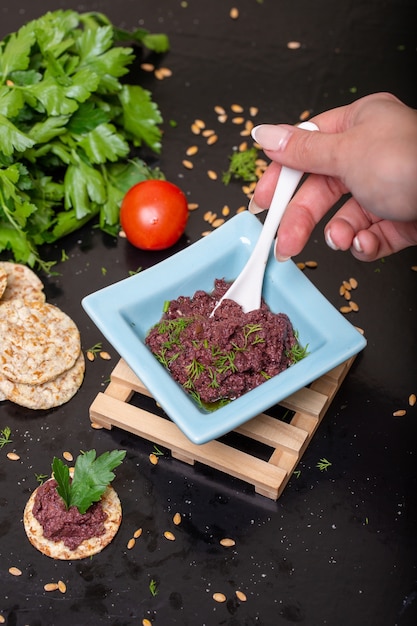 Kostenloses Foto vertikale nahaufnahme einer person, die olivenpaste auf cracker auf dem tisch unter den lichtern setzt