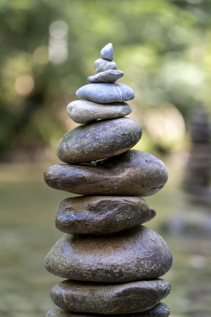 Vertikale Nahaufnahme einer Pyramide aus Steinen, die auf einem Flusswasser ausbalanciert ist