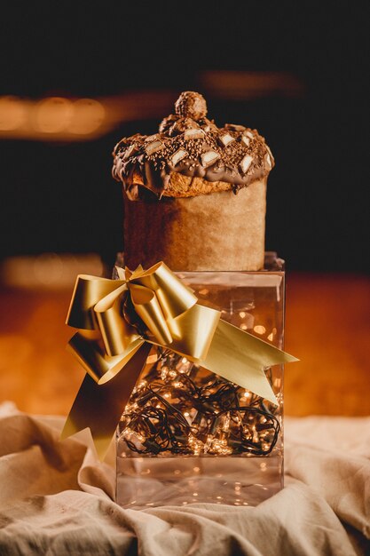 Vertikale Nahaufnahme einer romantischen Box mit Lichtern, einem goldenen Band und einem Muffin