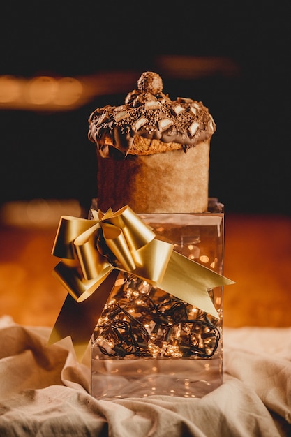 Vertikale Nahaufnahme einer romantischen Box mit Lichtern, einem goldenen Band und einem Muffin