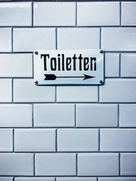 Vertikale Nahaufnahme eines Toilettenzeichens mit einer deutschen Schrift