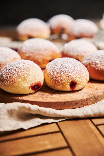 Kostenloses Foto vertikale nahaufnahme von flauschigen donuts gefüllt mit marmelade auf einem tablett auf dem tisch unter den lichtern