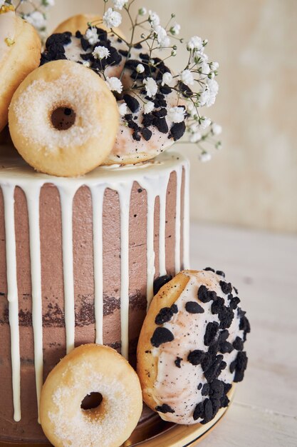 Vertikale Nahaufnahme von köstlichem Donut-Choco-Geburtstagskuchen mit Donuts oben und weißem Tropf