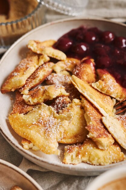 Vertikale Nahaufnahmeaufnahme von köstlichen flauschigen Pfannkuchen mit Kirsche und Puderzucker