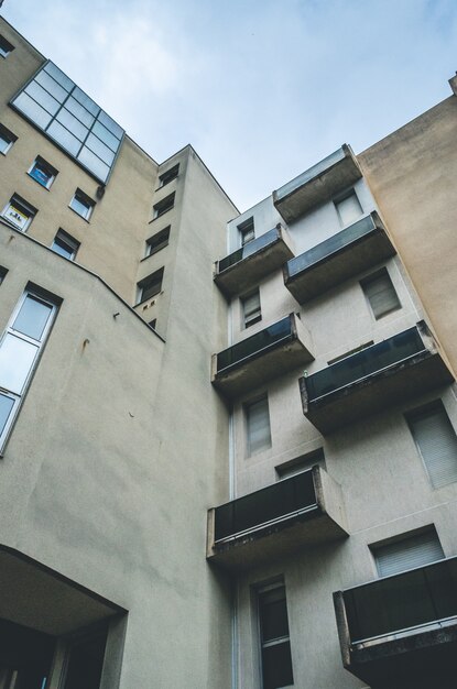 Vertikale niedrige Winkelaufnahme eines braunen abstrakten Architekturgebäudes mit Balkonen und Fenstern