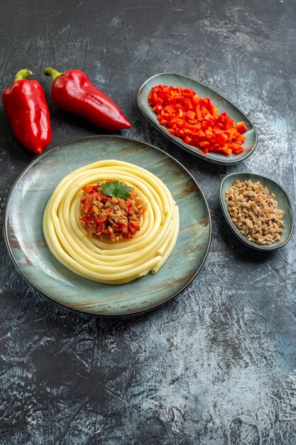 Vertikaler Blick auf köstliche Pastagerichte auf einem blauen Teller, serviert mit Tomaten und Fleisch zum Abendessen und seinen Zutaten