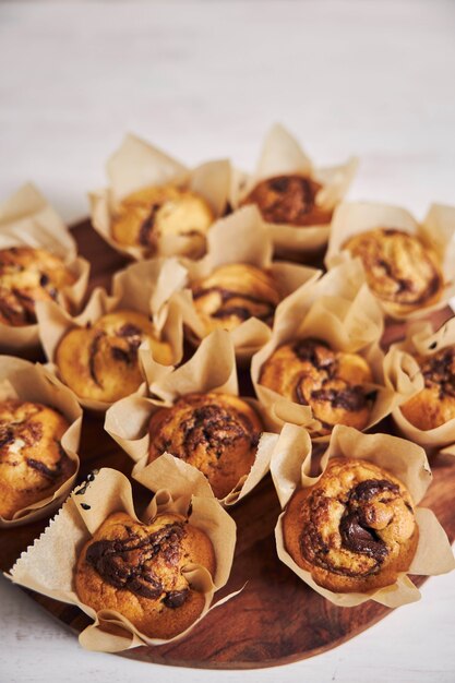 Vertikaler Hochwinkelschuss des köstlichen Schokoladenmuffins auf einem Holzteller auf einem weißen Tisch