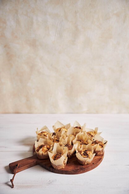Vertikaler Hochwinkelschuss des köstlichen Schokoladenmuffins auf einem Holzteller auf einem weißen Tisch