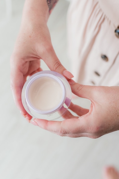 Vertikaler Hochwinkelschuss einer Frau in einem rosa Kleid, das eine kleine Tasse Milch hält