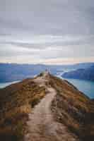 Kostenloses Foto vertikaler hochwinkelschuss einer person, die am ende der gehstraße auf roys peak in neuseeland steht