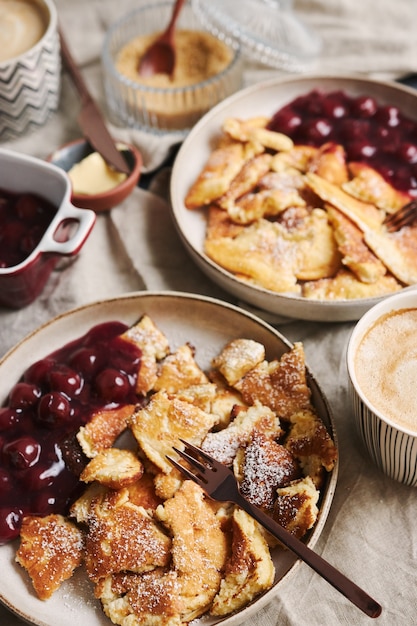 Vertikaler Hochwinkelschuss von köstlichen flauschigen Pfannkuchen mit Kirsche und Puderzucker