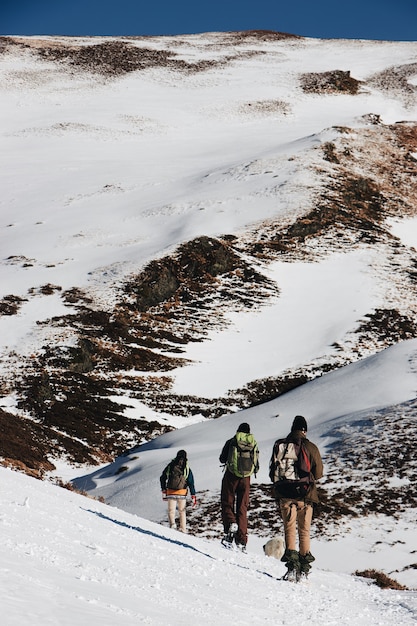 Kostenloses Foto vertikaler hochwinkelschuss von wanderern mit rucksäcken in den schneebedeckten bergen