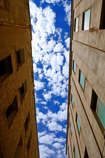Vertikaler niedriger Winkelschuss zwischen zwei Gebäuden mit bewölktem Himmel