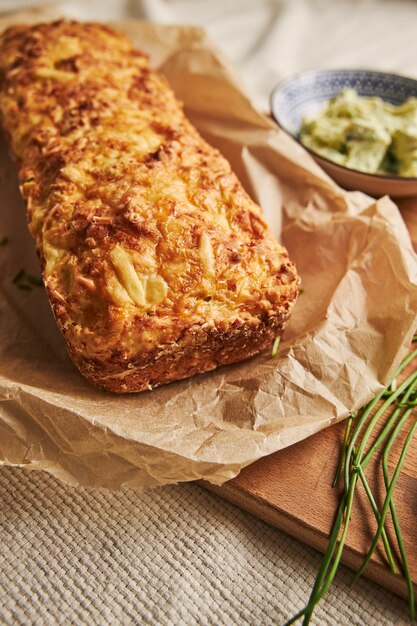 Vertikaler Schuss Brot mit Käsekräuterbutter auf einem Holz