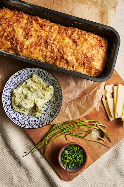 Kostenloses Foto vertikaler schuss brot mit käsekräuterbutter auf einem holz