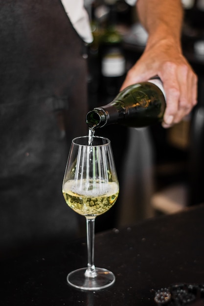 Vertikaler Schuss des Barkeepers, der Wein in ein Glas gießt