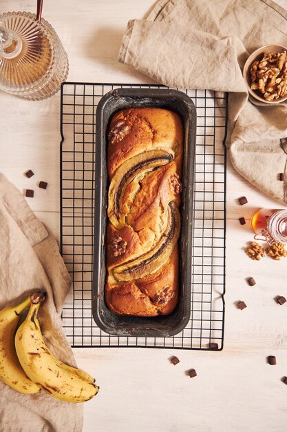 Vertikaler Schuss des köstlichen Bananenbrotes in einer Laibpfanne mit Schokoladenstücken und Walnuss auf einem Tisch