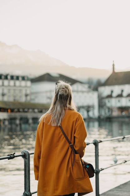 Vertikaler Schuss einer blonden Frau mit einer gelben Jacke auf einer Brücke