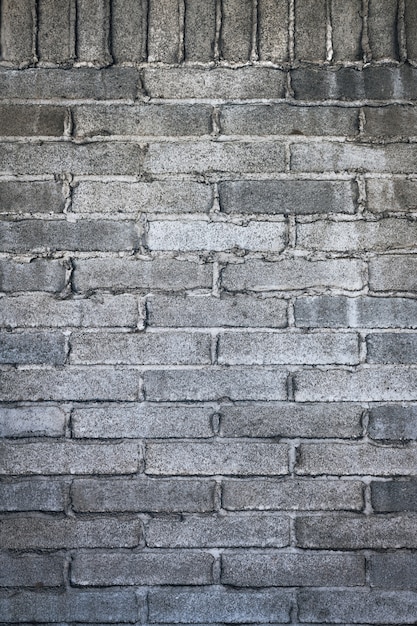 Vertikaler Schuss einer grauen gemauerten Wand mit Zement