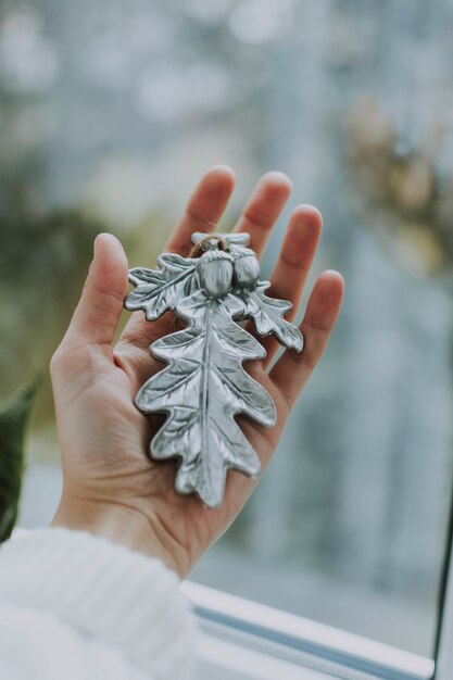 Vertikaler Schuss einer Person, die eine Christbaumverzierung hält