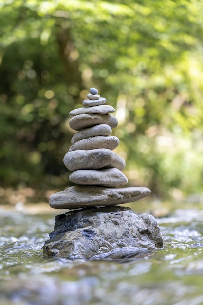 Vertikaler Schuss einer Pyramide aus Steinen, die auf einem Flusswasser balanciert ist