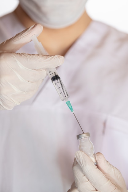 Vertikaler Schuss eines Arztes, der einen Impfstoff hält - das Konzept des Koronavirus