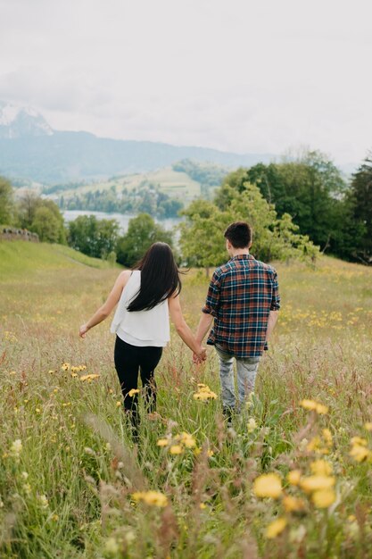 Vertikaler Schuss eines liebenden jungen Paares, das im Feld geht