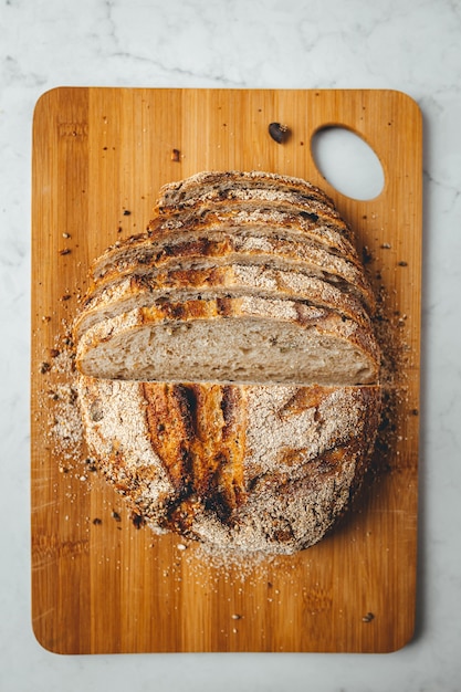 Vertikaler Schuss von frischem Sauerteigbrot auf hölzernem Schneidebrett