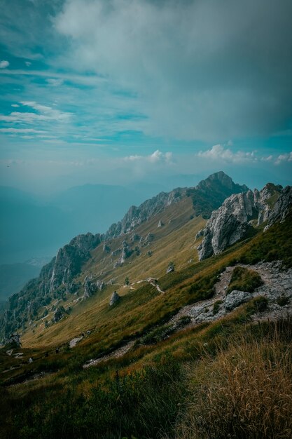 Vertikaler Schuss von grasbewachsenen Hügeln mit Felsen und Berg in der Ferne