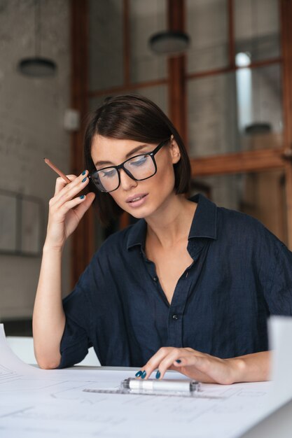 Vertikales Bild der nachdenklichen Geschäftsfrau in Brillen