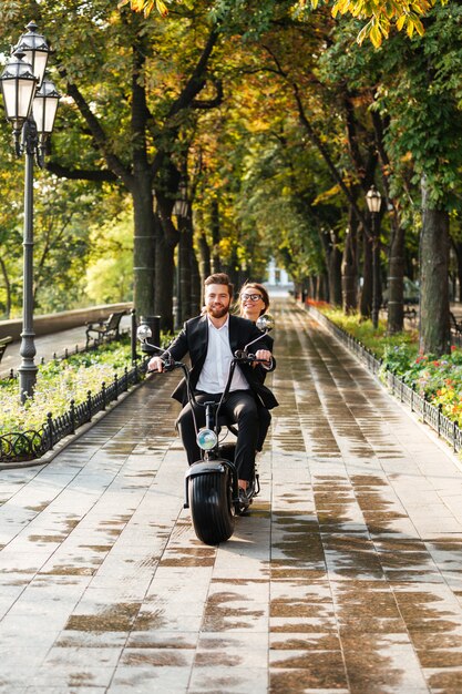 Vertikales Bild des glücklichen eleganten Paares reitet auf modernem Motorrad