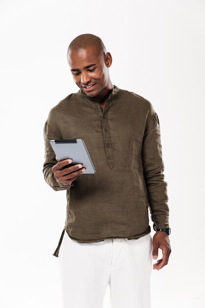 Vertikales Bild des lächelnden afrikanischen Mannes unter Verwendung des Tablet-Computers