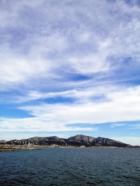 Kostenloses Foto vertikales bild des meeres, umgeben von felsen unter einem bewölkten himmel in marseille in frankreich