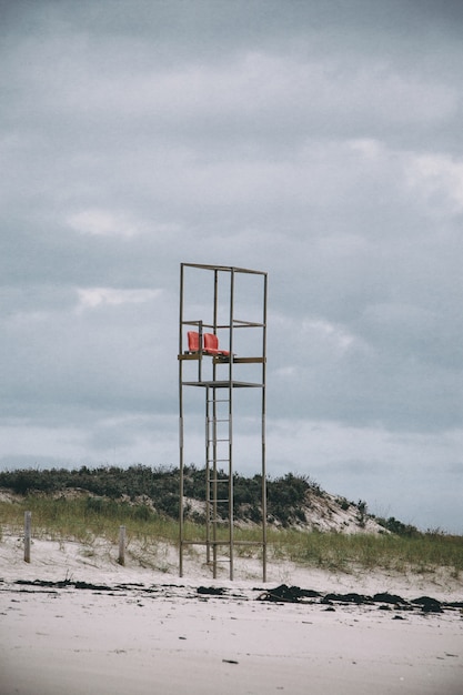 Vertikales Bild eines Rettungsschwimmerturms in einem Strand unter einem bewölkten Himmel während des Tages
