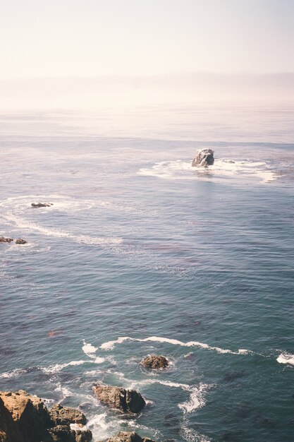 Vertikales Bild von Felsen auf dem Ozean nahe einem Klippenufer