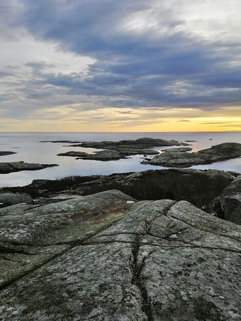 Vertikales Bild von Felsen, die durch das Meer während des Sonnenuntergangs in Rakke in Norwegen umgeben sind