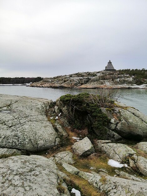 Vertikales Bild von Felsen, die durch den Fluss unter einem bewölkten Himmel in Norwegen umgeben sind