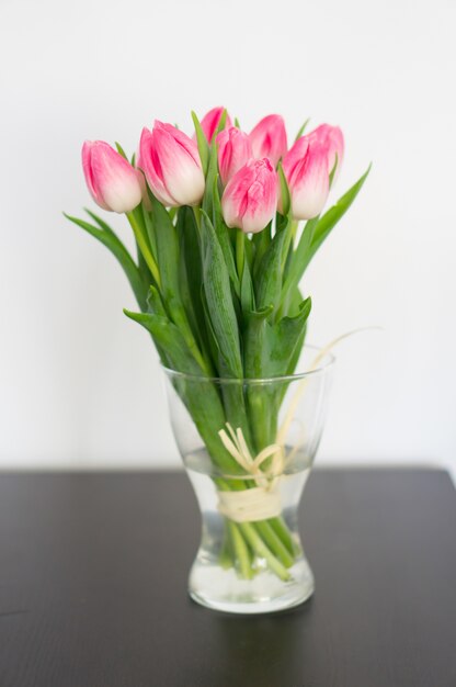 Vertikales Bild von Tulpen in einer Vase auf dem Tisch unter den Lichtern