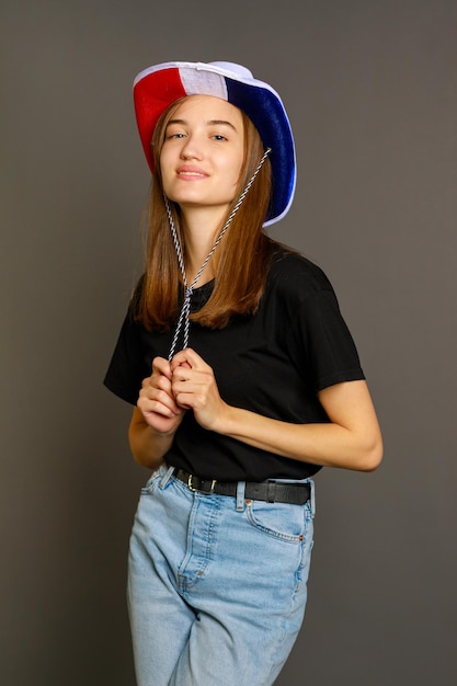 Vertikales Foto einer jungen Dame, die auf grauem Hintergrund steht und in die Kamera schaut