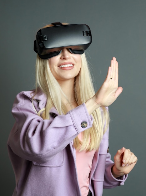 Vertikales Foto einer jungen Dame, die eine VR-Brille trägt und ihre Hand in der Luft offen hält