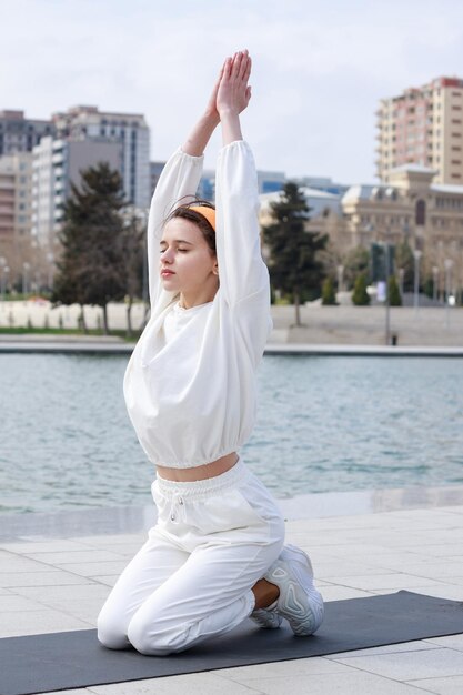 Vertikales Foto einer jungen Dame, die ihre Meditation vor dem See macht Foto in hoher Qualität