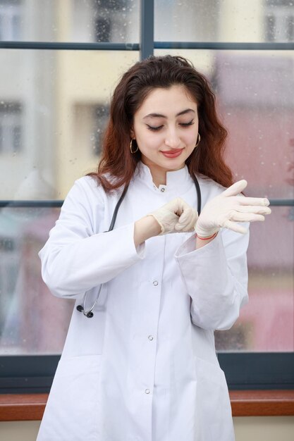 Vertikales Foto einer jungen weiblichen Gesundheitspflegekraft, die Handschuhe trägt Foto in hoher Qualität