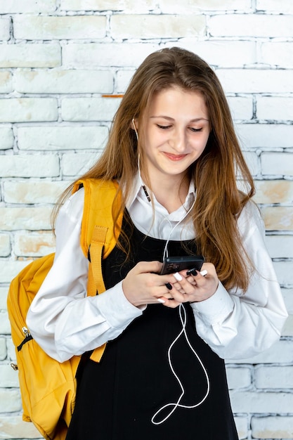 Vertikales Foto eines entzückenden Studenten, der mit dem Telefon spielt Foto in hoher Qualität