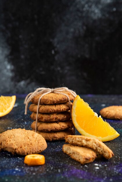 Vertikales Foto eines Stapels hausgemachter Kekse mit Orangenscheibe über der Weltraumoberfläche