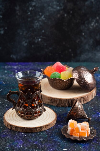 Vertikales Foto von bunten Bonbons und duftendem Tee auf blauer Oberfläche