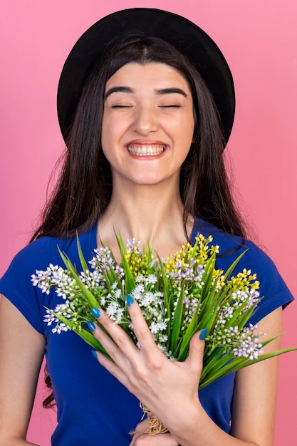 Vertikales Porträt eines jungen Mädchens, das Blumen hält und lacht