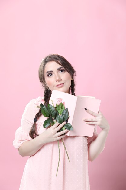 Verträumte Frau, die Rosen und Buch hält